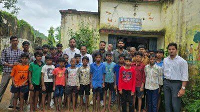 खल्लारी के जर्जर आदिवासी प्री-मैट्रिक बालक छात्रावास के बाहर खड़े बच्चे और अधिकारी।