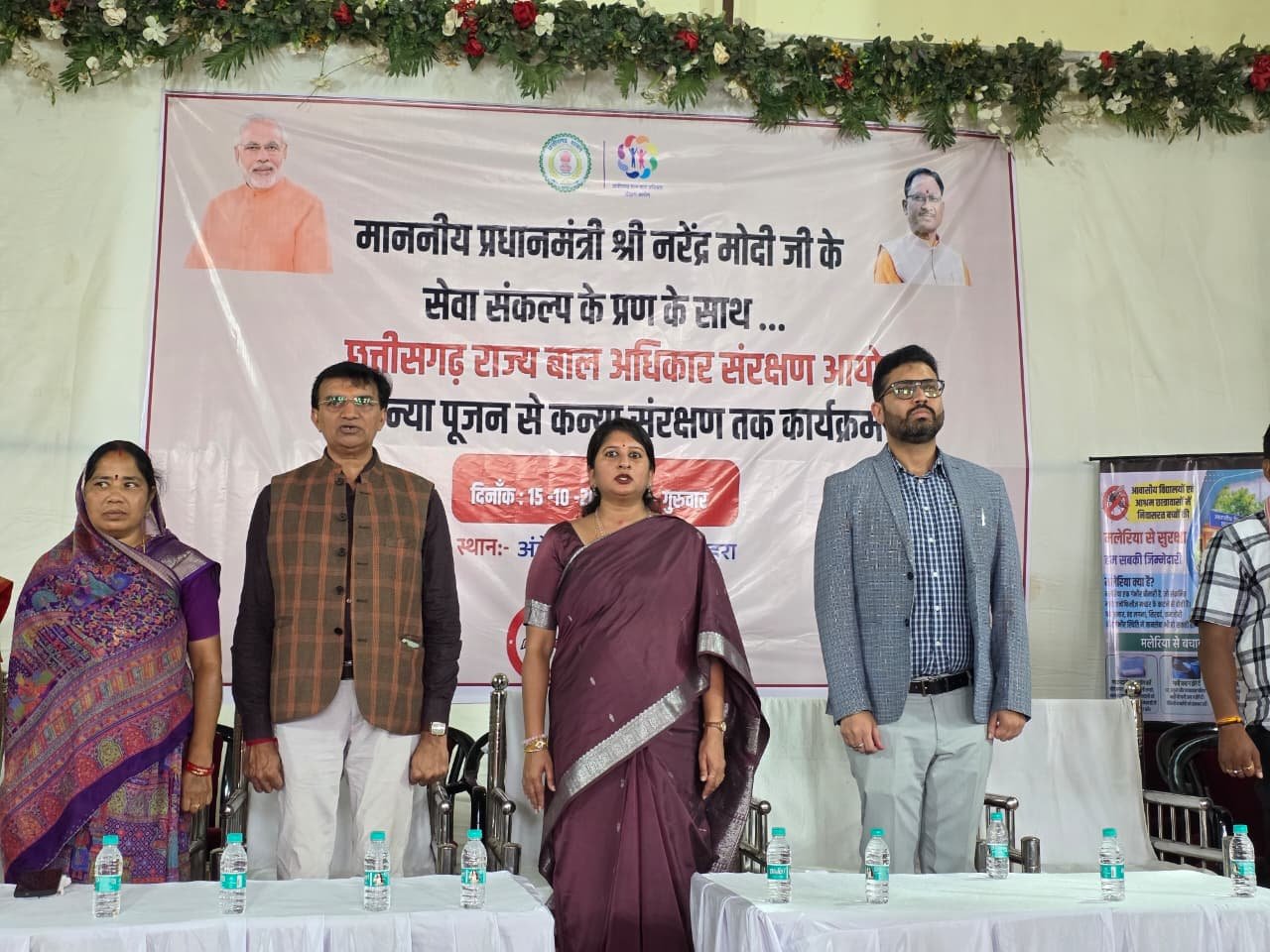 मंच पर अतिथि और कार्यक्रम का बैनर